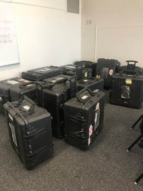 Photo of large black Pelican cases. All clinic materials and equipment arrive in these cases.